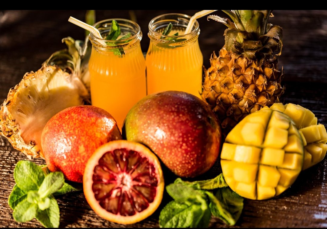 Cloudy tropical juice bottles with cut mango and blood orange