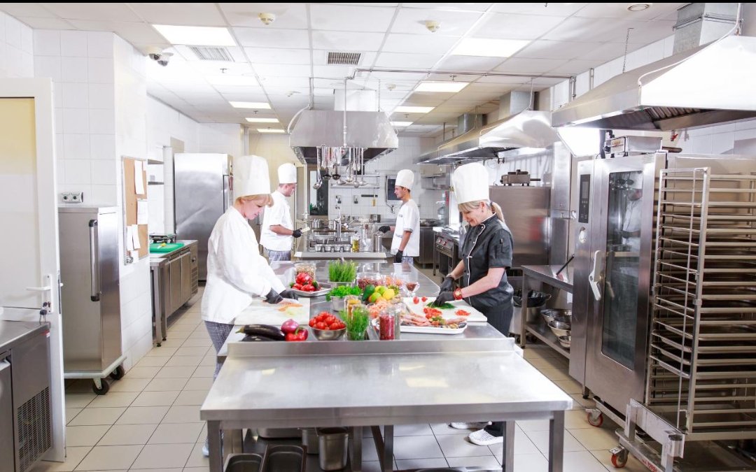 Chefs working at stainless steel stations in a commercial kitchen